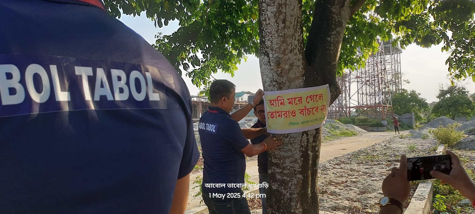 Abol Tabol volunteers tying awareness signs on trees at Dhupguri Railway Station
